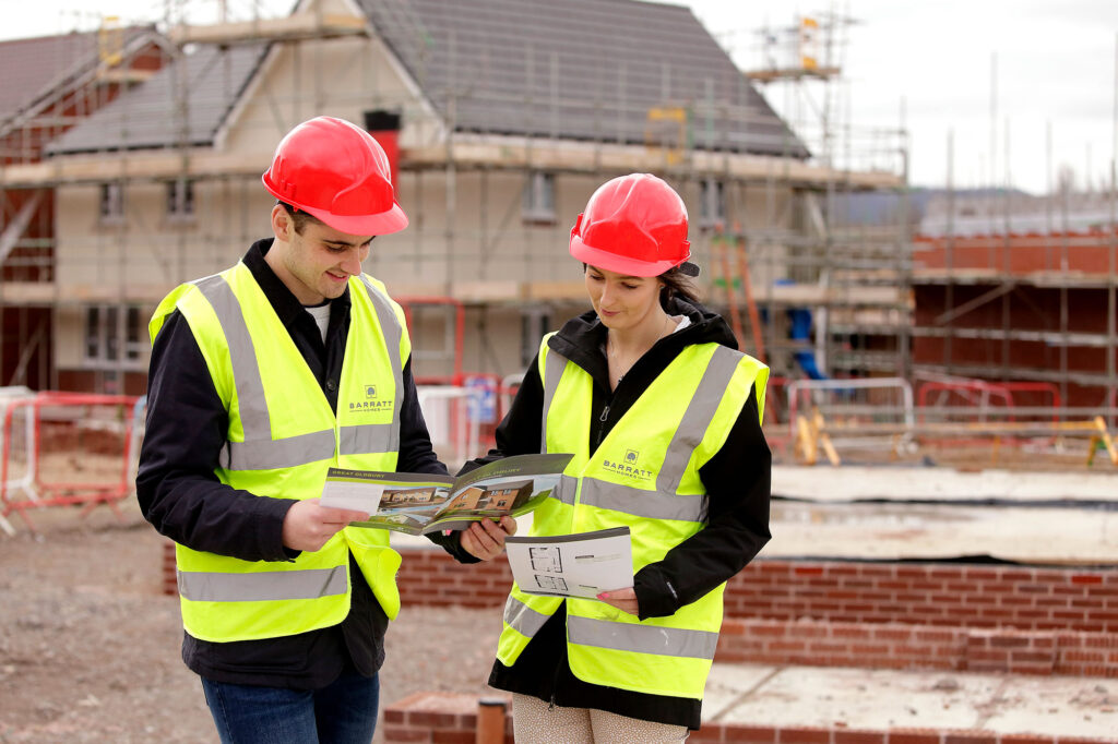 Young couple looking at their new build home on a building site