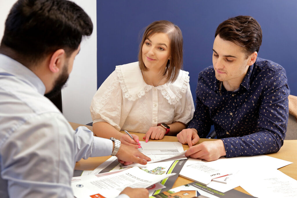 Young couple signing contract with a mortgage advisor from Dupree and Co